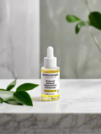 A bottle of Aromanesque Natural Retinol-Alternative Oil Serum placed on a marble surface with a plant in the background.